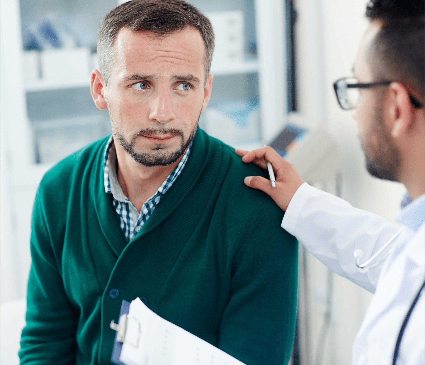 A doctor is comforting a worried looking man